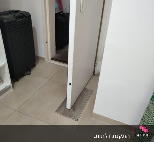 דלת לבנה פתוחה עם ידית לבנה על רצפה מרוצפת